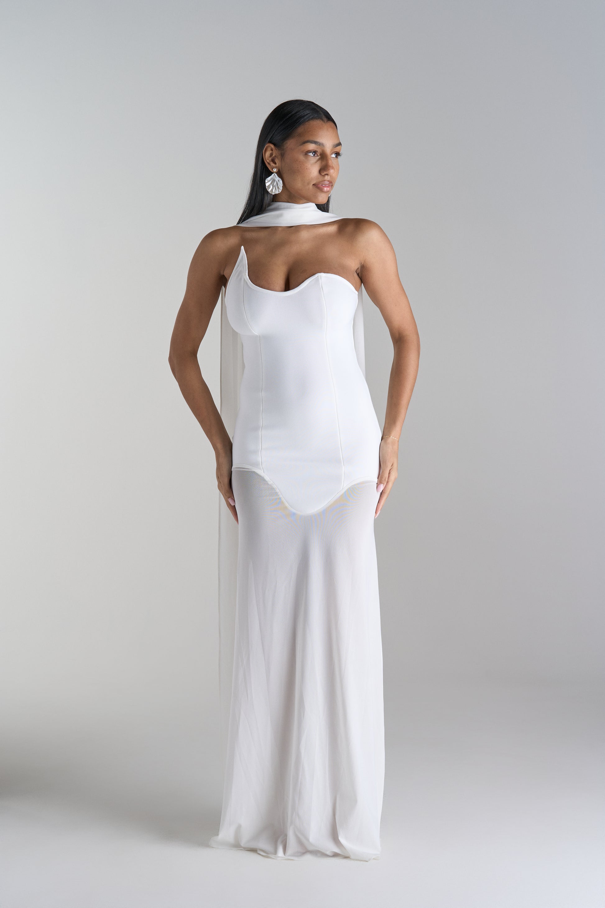 Model is wearing white dress with scarf
