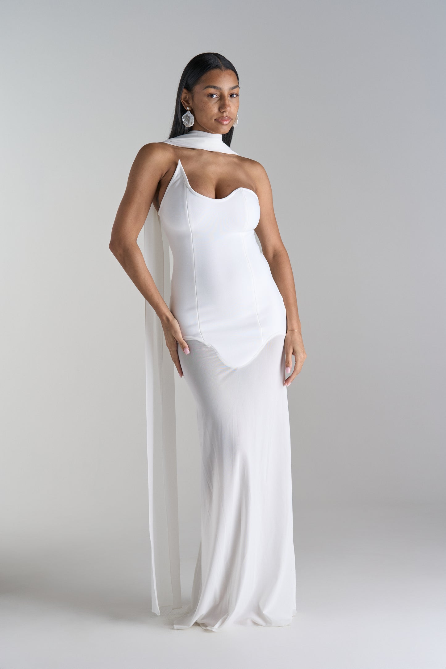 Model is wearing white dress with scarf