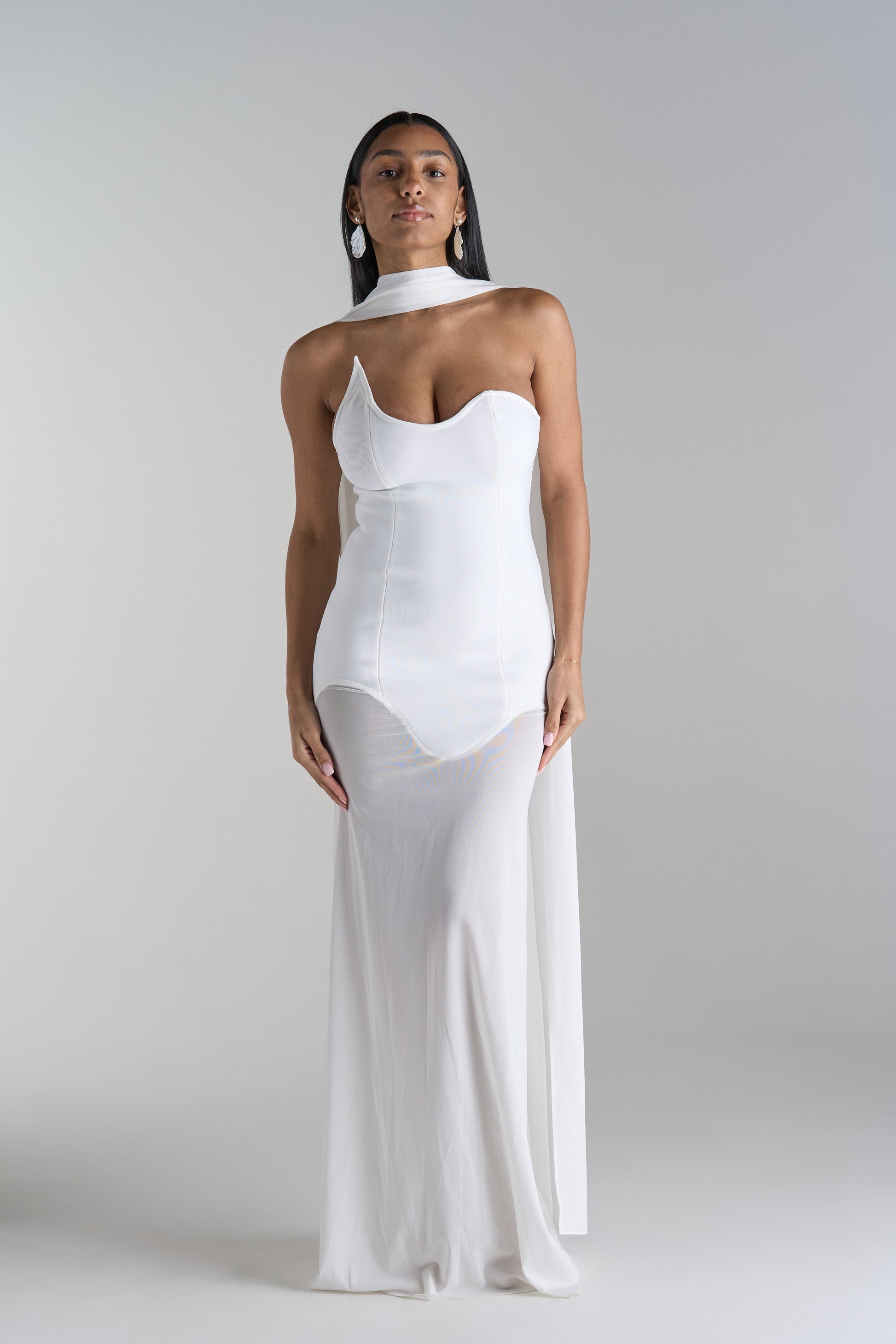 Model is wearing white dress with scarf