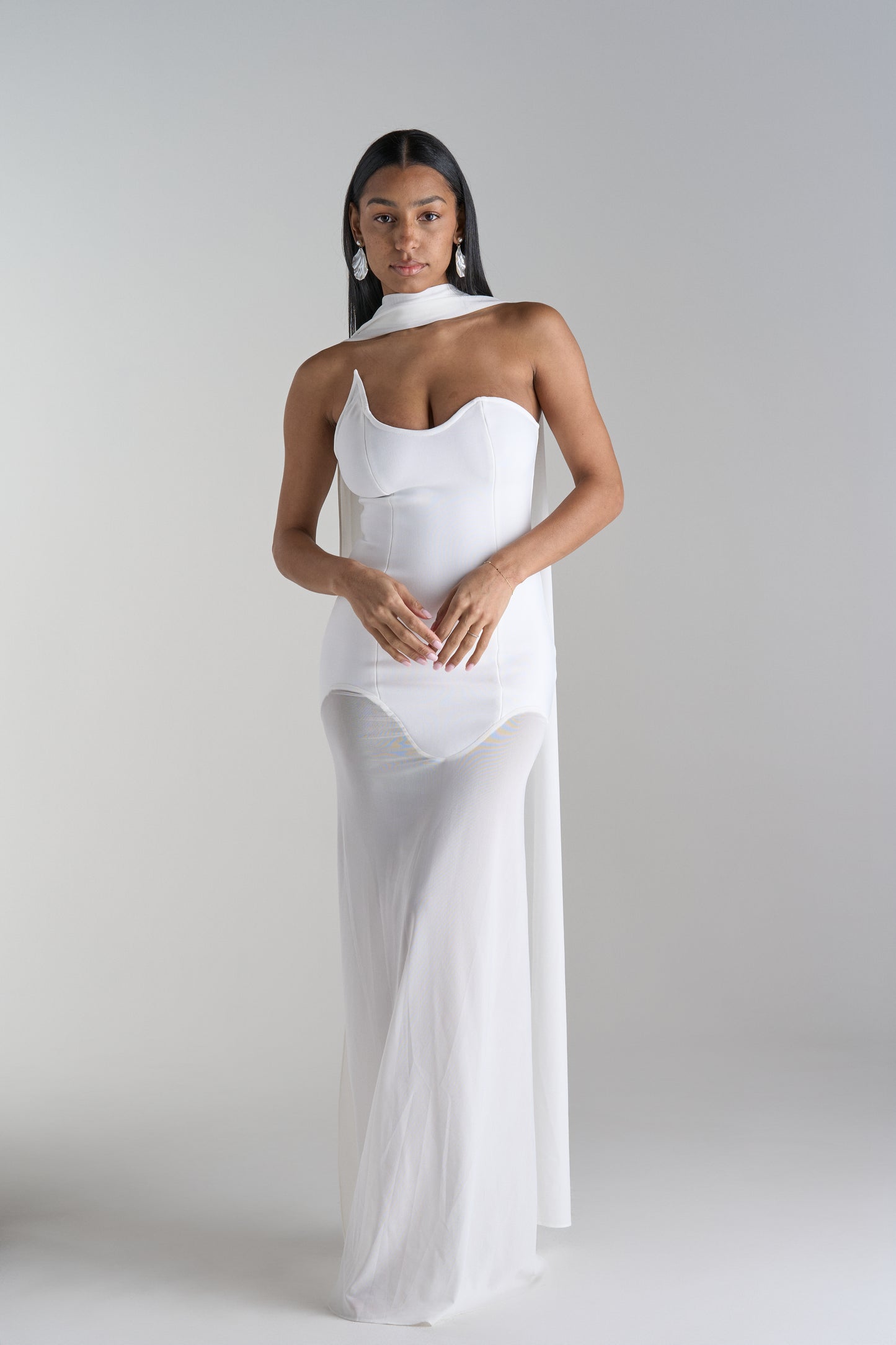 Model is wearing white dress with scarf