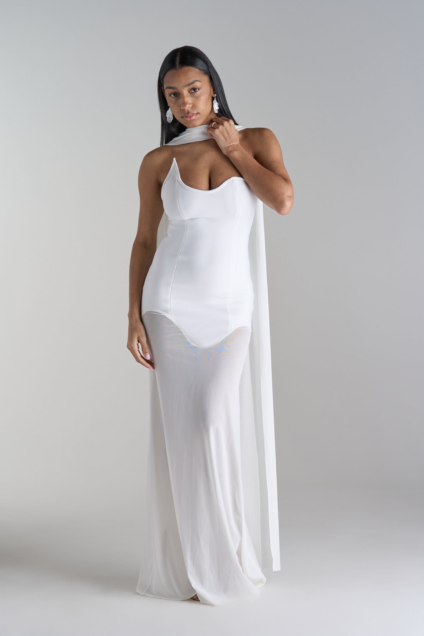 Model is wearing white dress with scarf