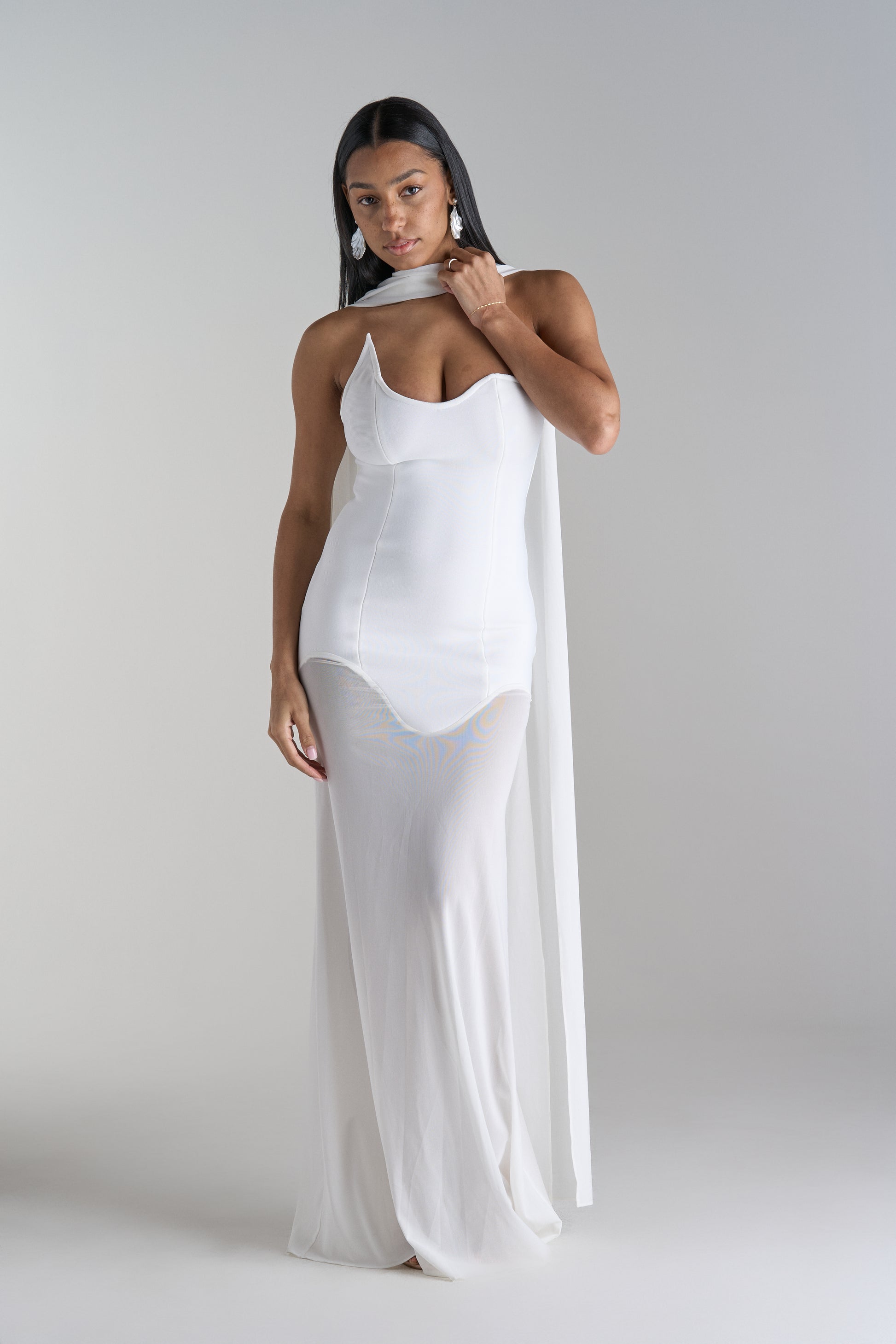 Model is wearing white dress with scarf